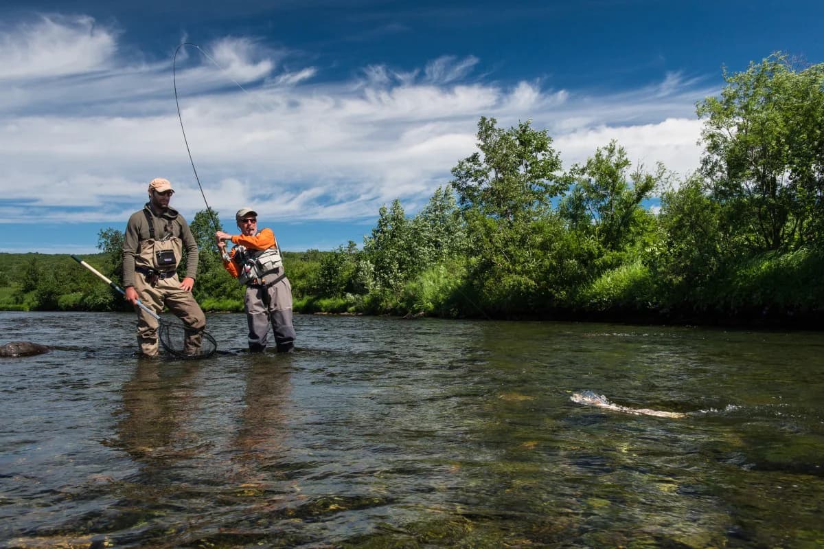 Fishing guide and client wade fishing in a river